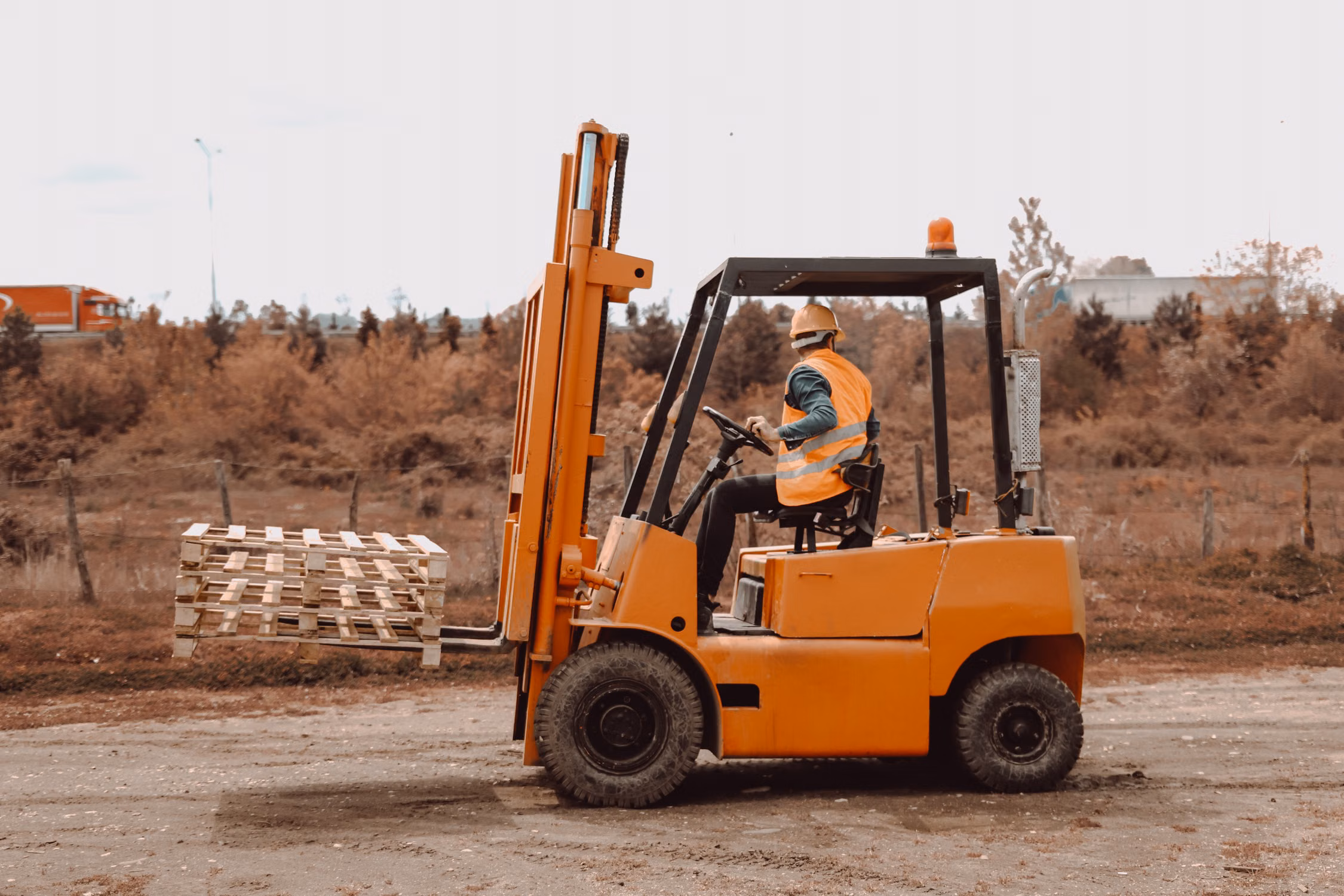Forklift operator transporting stacked pallets